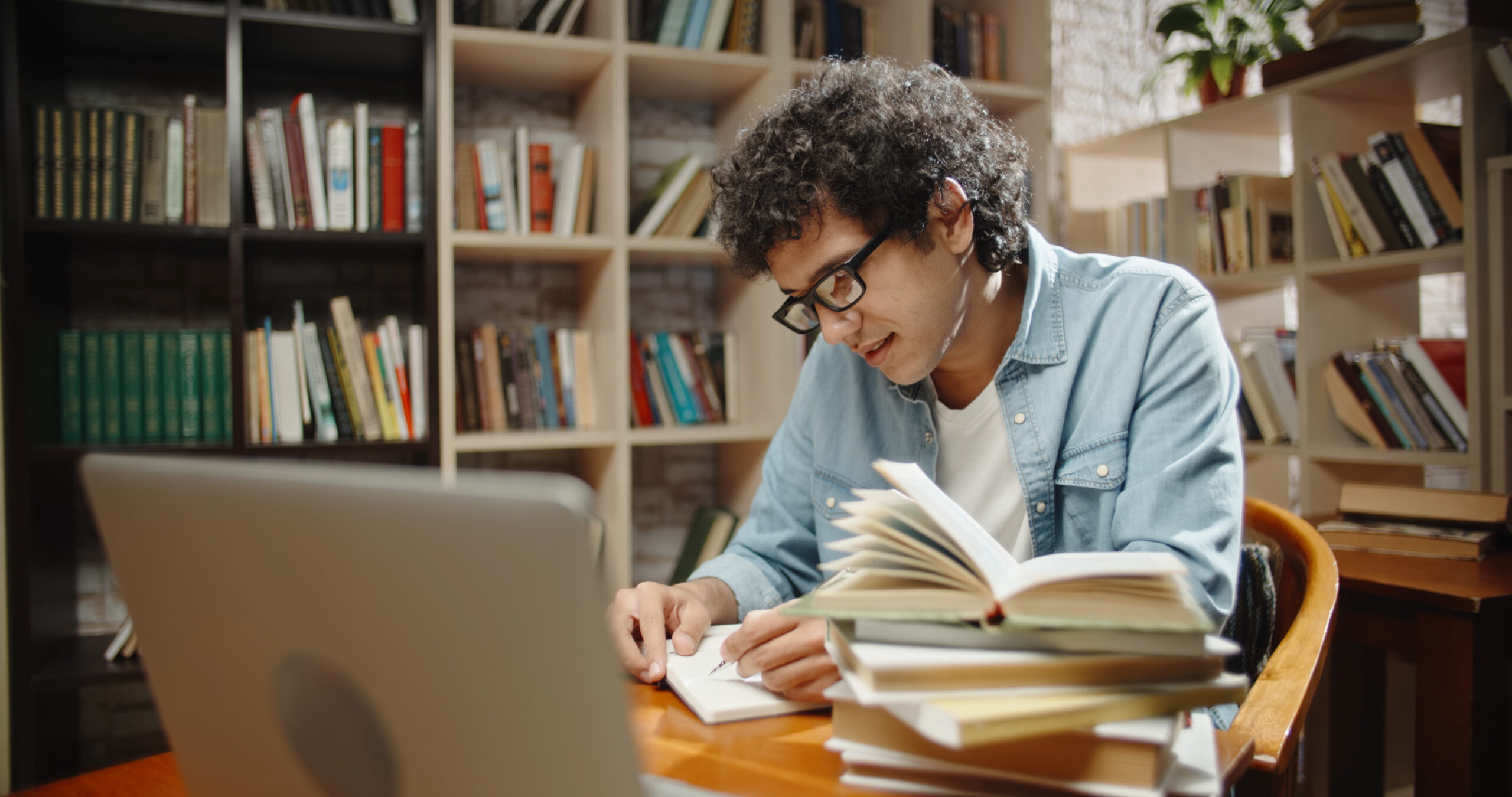 Estudiante rodeado de libros y delante del ordenador