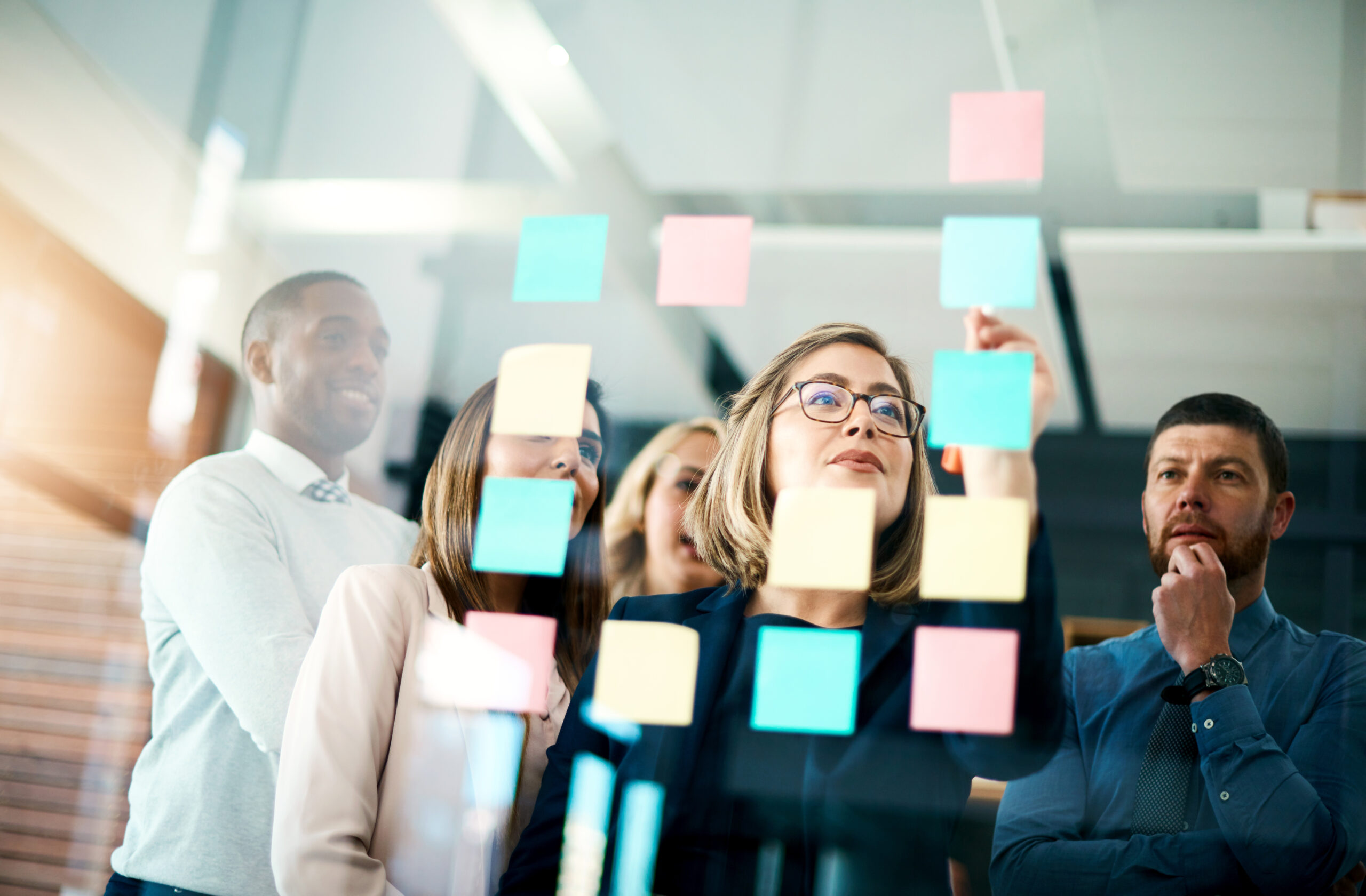 Grupo de personas contemplando una serie de post-it y ordenándolos